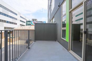 A black metal fence separates a parking lot from a building. at RiDE at RiNo Apartments, Denver 80216